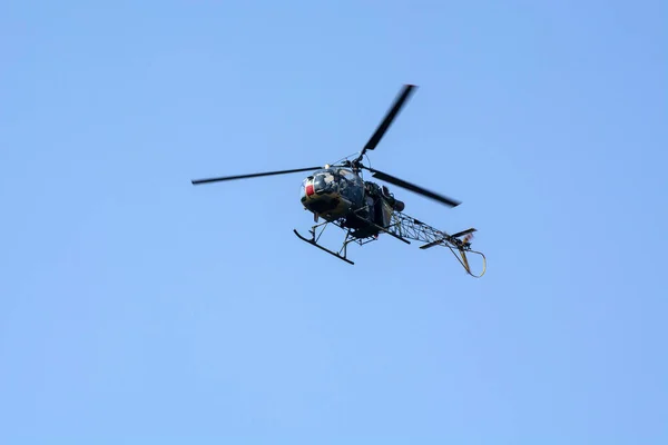 Close-up of combat helicopter is flying against isolated blue sky.