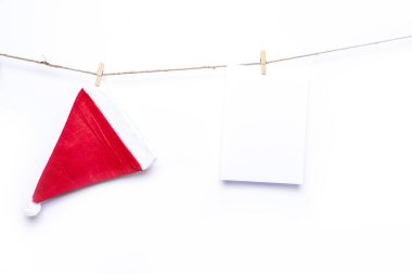 Noel Baba şapkası ve boş beyaz kağıt, izole edilmiş beyaz arka plana karşı bir ipe asılmış.