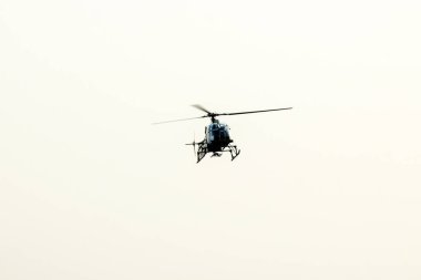 Siluet helikopter gökyüzünün ortasında uçuyor.