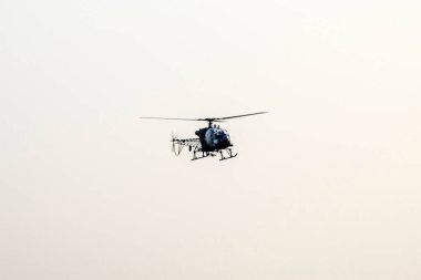 Siluet helikopter gökyüzünün ortasında uçuyor.