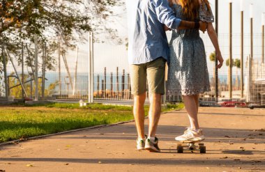 Genç bir adamın, asfalt yolda asfalt yolda kız arkadaşına sarılıp yardım edişinin arka plan görüntüsü.