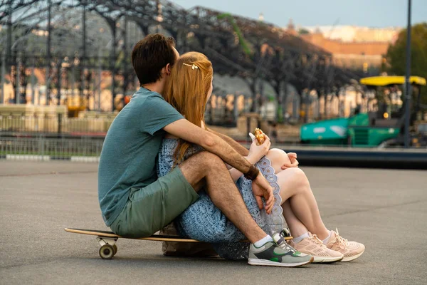 Back View Young Couple Sitting Together Longboard Blurred Cityscape Looking — Stock Photo, Image