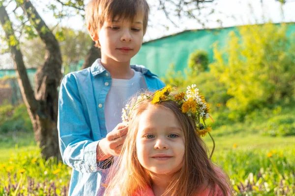 Ağabeyi Kafasına Çiçek Çelengi Koyarken Kameraya Bakan Sevimli Küçük Kız — Stok fotoğraf