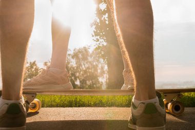 Genç bir çift yaz gökyüzüne karşı yan yana ve uzun tahtanın üzerinde duruyor..