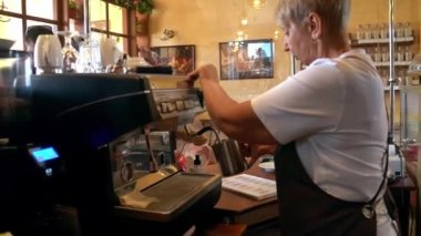 Meçhul, olgun bir kadının kahve ekipmanları kullanarak içecek hazırlarken yandan görünüşü. Küçük kafede çalışan bir barista..