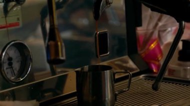 Kahve makinesinden metal fincana sıcak kahve dökülüyor. 