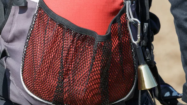 stock image Metal bear bell hanging from hiker red backpack