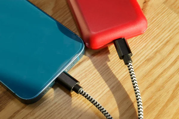 Kablolara bağlı kırmızı ve mavi cep telefonlarının arkası