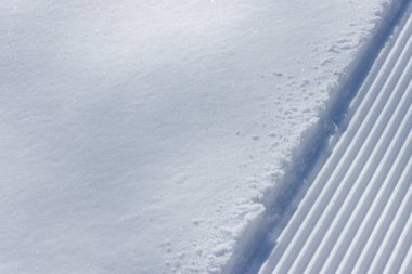 Bakımlı bir kayak yamacının kenarında ve taze beyaz kar.