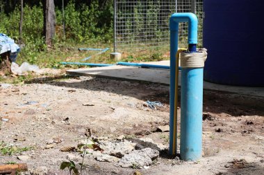 Yeraltı kuyularının PVC boruları. Kırsal artezyen kuyusu fotovoltaik enerjili denizaltı pompası toprak teraslı arka planda ve kırsal alanda kuru yapraklar var. Seçici odak