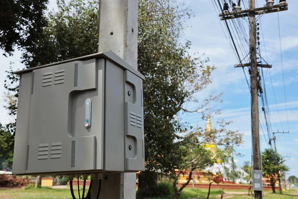 Electrical control cabinet on lamp post. Close-up of waterproof metal cabinet for connection and control of high voltage systems mounted on concrete poles on shallow sky background with copy space.