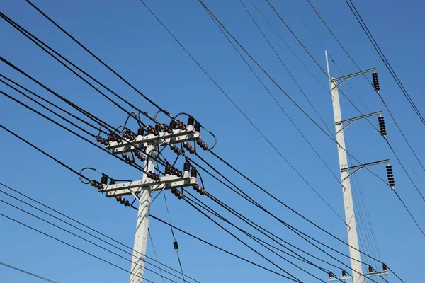 極に高電圧線を持つ電極 青い空の背景に都市分布のためのコンクリート極の金属腕の上に中断セラミック絶縁体との伝送ライン — ストック写真