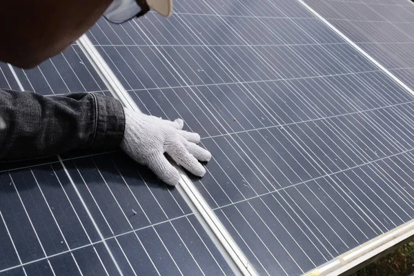Engineers inspecting solar panels. A close-up of the engineer\'s hand inspecting solar cells closely in farm electricity generation with copy space. Selective focus