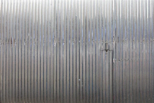 Silver zinc background. Silver corrugated metal wall or partially torn galvanized steel surface. Background wall with selective focus