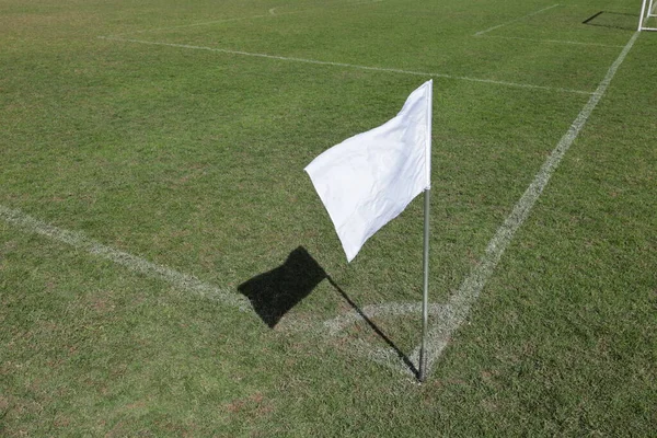 Corner flag on a soccer field. Closeup of white corner flag with shadow on green soccer field with copy space and selective focus.
