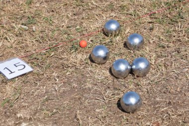 Boules in the lawn. Close-up of steel balls of traditional French game of petanque in an outdoor racetrack during holidays with copy space and focus. clipart