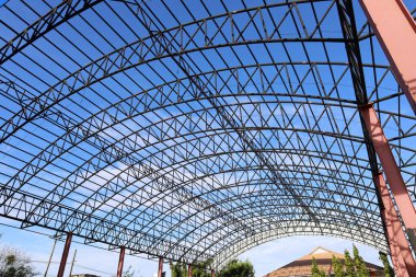 Metal structure of the dome. Detail of black steel structure of large dome in bottom view on bright blue sky background with selective focus.