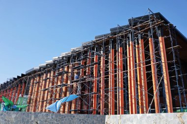 Metal scaffolding structure in front of a building. Side scaffolding for maintenance or real estate renovation on blue sky background with copy space and selective focus.