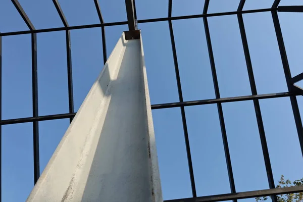 Steel columns of the roof structure. Closeup of white metal column supporting roof structure of house or building on blue sky background in bottom view with copy space and focus.