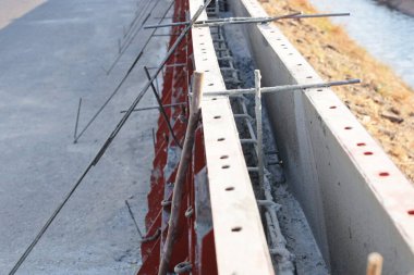 Metal biçiminde inşaat iskeleti. Çubukları ve deforme olmuş parmaklıkları beton bariyerlerle güçlendirerek kanal kenarında seçici bir odak noktasıyla çalışmak.