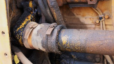 Dirty hose connectors. Closeup of old rubber hose with dust and oil stains fastened with clamp to connect heavy engine metal hose with copy space. selective focus