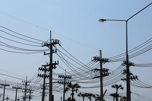Silhouette of a strong electric line on a pole. Many high voltage transmission lines in front of a substation on the side of a highway in an urban area on a blue sky background. selective focus