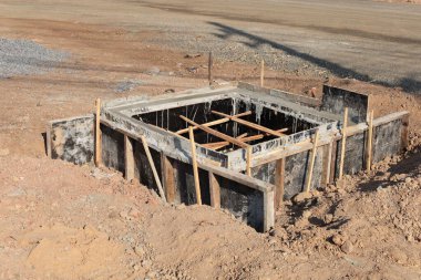 Construction of the main sewer. Reinforced concrete formwork for the construction of a sewer pipe on the side of a highway in an urban area on gravel soil background. selective focus