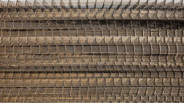 Wire mesh heap background. BRC rusty welded steel wire mesh for concrete slab reinforcement on floor construction site in natural daylight side view with copy space and selective focus.