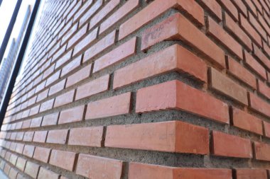 Red brick wall corner. Closeup of red brick and orange brick border with concrete wall of modern building or house with copy space with selective focus. clipart