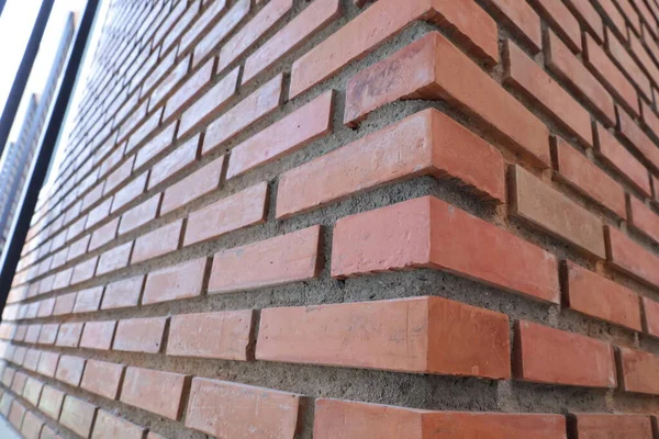 Red brick wall corner. Closeup of red brick and orange brick border with concrete wall of modern building or house with copy space with selective focus.