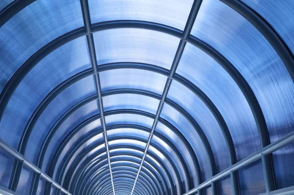 Corridor metal roof structure. Closeup of vaulted metal roof arches covered with blue polycarbonate sheets to block sunlight and rain for people walking between buildings in selective focus.
