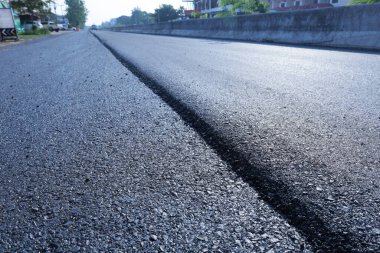 Yolda sığ asfalt derinliği. Farklı asfalt yol yüzeyinin yolun ortasında yan görünümü kapatılırken, bir yandan da seçici odaklı kopyalama alanı ile inşaat veya yenileme çalışmaları yapılıyor..