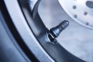 Motosiklet lastiği vanası. Lastik valf sapını seçici odaklı motosiklet tekerine yakın çekimde tut.