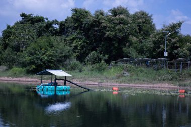 Havuzdaki bir şamandırada güneş suyu pompası. Tayland 'ın kırsal kesimlerinde fotokopi alanı olan bir çiftlikte su pompalamak için galvanize edilmiş çatısı olan yüzen bir şamandıraya alternatif enerji pompası. seçici odak