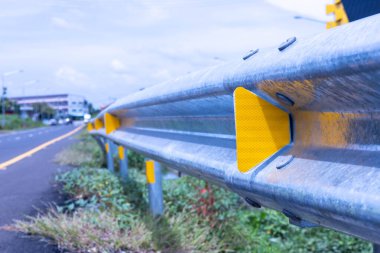 Korkuluklarda sarı trafik yansıtıcıları var. Yol kenarındaki metal bariyerlere kurulmuş yansıtıcı panellerin kapatılması, karayolu kullanıcılarının gece veya kötü hava koşullarında seçici bir odaklanma ile güvenli araç kullanmalarına yardımcı olur.