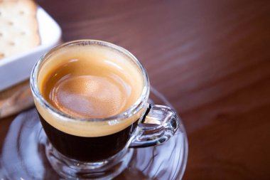 Bardakta Espresso kahvesi. Kahverengi bir masada, fotokopi alanı olan bir bardakta sade kahve. Seçici odak