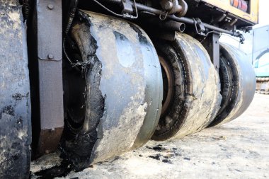 Eski ve hasarlı yol tekerlekli lastikleri. Titreşimli asfalt sıkıştırıcının kırık eski tekerleklerini kapatın. Fotokopi uzayı olan kirli motor yağı lekeleriyle birlikte. Seçici odak