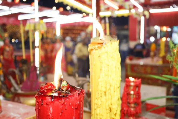 Light candles to worship gods in Chinese shrines. Closeup of yellow flame on large red and white candle with copy space and selected focus.