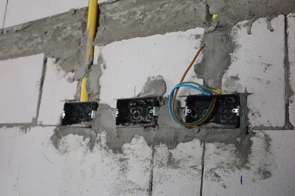 Holes in the wall for sockets with wires. Installing sockets on the wall of a house with wires protruding to prepare for supplying the electrical system in a house that is under construction. Select focus