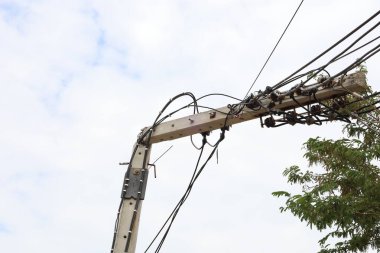 Kırık beton elektrik direği. Kırık ve bükülmüş beton bir direk, düşük voltajlı kablolarla mavi gökyüzü arka planında seçici odaklı elektrik direğinin ucunda..