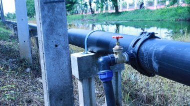 Hdpe borusunda su vanası var. Saddle Clamp bağlantısındaki su kesme vanası, tüketicilere ana su borusundan fotokopi alanı ve odak seçimi olan beton iskele üzerindeki su tedarik etme noktasını gösteriyor.