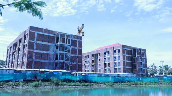 stock image Twin Towers Under Construction. Construction of red brick residential building with cranes lifting the side of the canal on a clear blue sky background and selective focus.