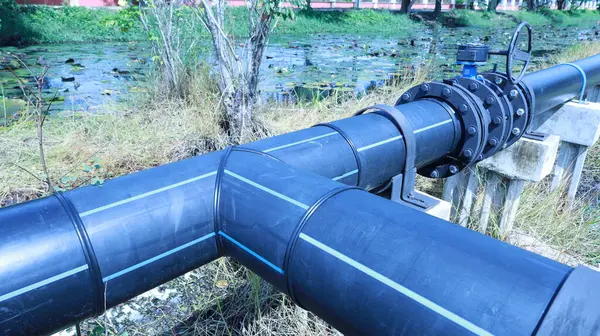 Hdpe su tedarik borusunda üçlü. Ana su tedarik borusunun sıcak kaynaklı polietilen boru hattını kapayın. Açık havada, parlak güneş ışığında fotokopi alanı olan beton iskelede..