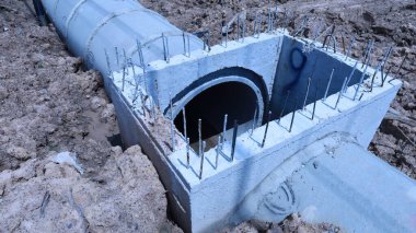 Beton borusu. Tamamlanmamış inşaat sahasındaki kanalizasyon borularını kapatın. Kopya alanı ve seçici odak noktası olan toprak çukurun yanındaki otoyolun yanında..