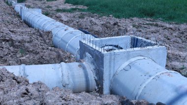 Üç yönlü beton drenaj borusu. Kanalizasyon boruları otobanın yanındaki inşaat sahasına yerleştirildi. Kopya alanı ve seçici odak noktası olan toprak çukurda..