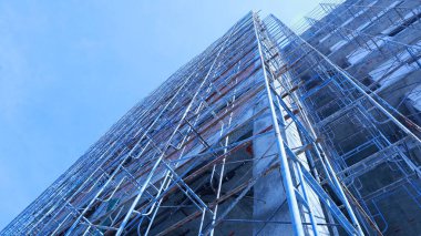 Yeni bir binanın yanındaki iskeleye. Yapım aşamasında olan bina, vinç ve gökyüzü zemininde bulunan ticari ya da iskan binalarının yanında bulunan metal iskeleler ve kopya alanı ve seçici odak noktası ile inşa ediliyor..