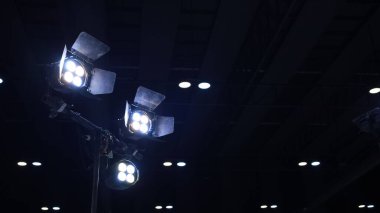Metal direğin üzerindeki LED sahne ışıkları. Bir ziyafet salonunda ya da karanlıkta fotokopi odası olan bir stüdyoda üç spot ışığı ve profesyonel ışıklandırma ekipmanı. Seçici odak
