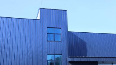 Modern minimalist geometrik arka plan. Depo, yüzeyinde ışık ve gölge olan dış metal levhaları seçici odaklı düşük açılı mavi gökyüzü arka planına karşı inşa ediyor..