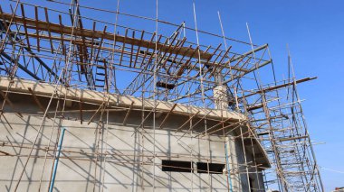 İnşaat duvarının yanındaki metal iskeleye. Açık hava inşaatında dayanıklılık için çelik iskelenin ve montaj parçalarının ayrıntıları alçak açılı arka planda. Seçici odak