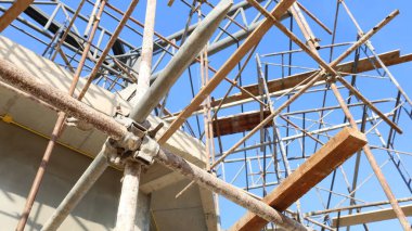 Eski iskele boru kıskacı. Kirli klempi kapat, binanın yan tarafındaki paslı metal boru iskelesini tut temiz gökyüzü arka planında fotokopi alanı ve seçici odaklı..